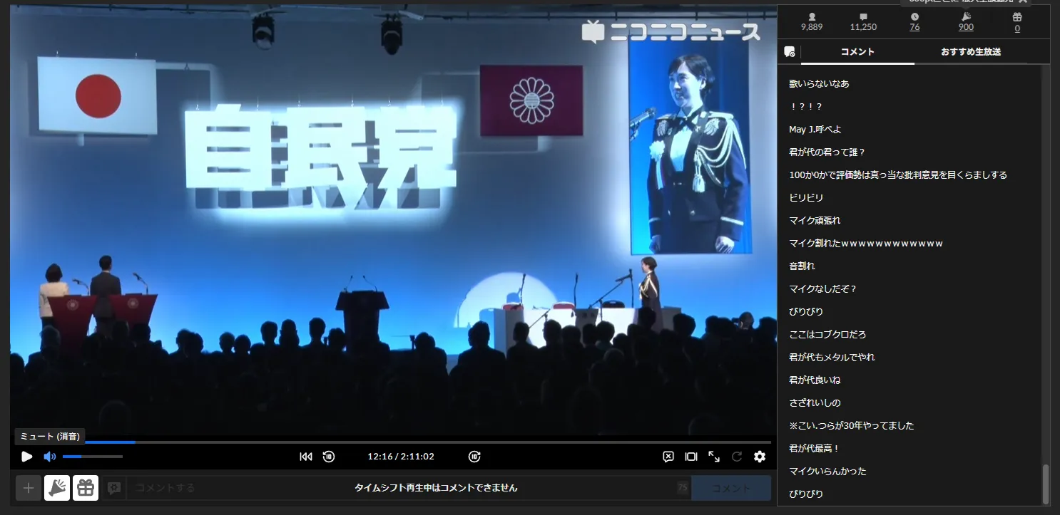 自民党党大会 ニコニコ生放送のスクリーンショット。開始12分16秒頃。壇上向かって右に鶫氏の姿が映し出されており、服装を確認できる。